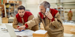  Carpenter talking on the phone while using computer in a workshop