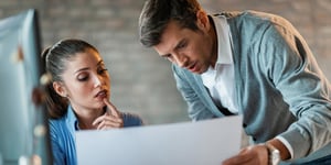 Two entrepreneurs cooperating while reading blueprints and working together in the office